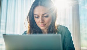 Woman typing on laptop, taking free 150-question Enneagram Matrix Test, initiating personalized AI and human coaching for comprehensive self-development