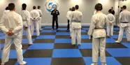 A large group of adult students listening to Master Gary Simmons during an in person class.