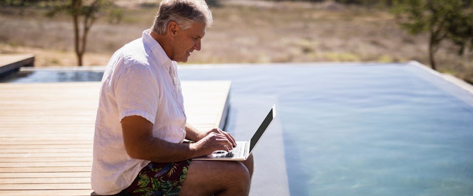elderly man on laptop by pool