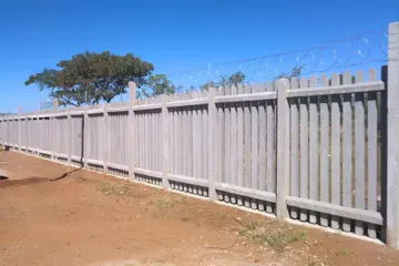 Inside view of a long concrete palisade fence showing the reinforced ground beam