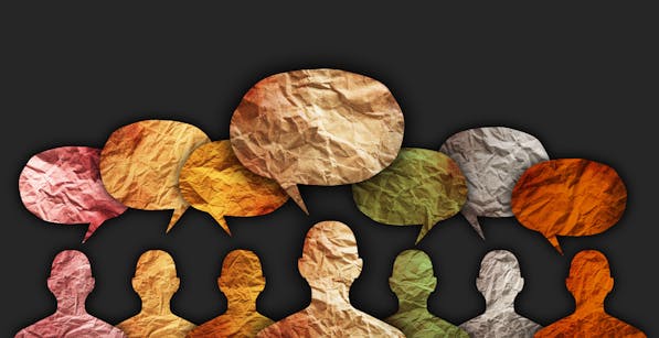 An array of crumpled paper cutouts in the shape of human heads and speech bubbles against a dark background, illustrating a colorful conversation or a diverse exchange of ideas.