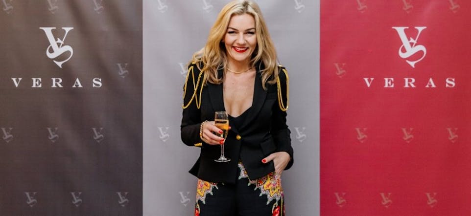 Vera smiling with a glass of champage at the VERAS Studio Launch