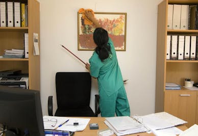 Lady cleaning behind desk in office
