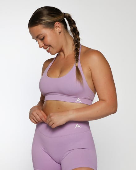 Fitness model in a cropped purple activewear top styled in studio lighting