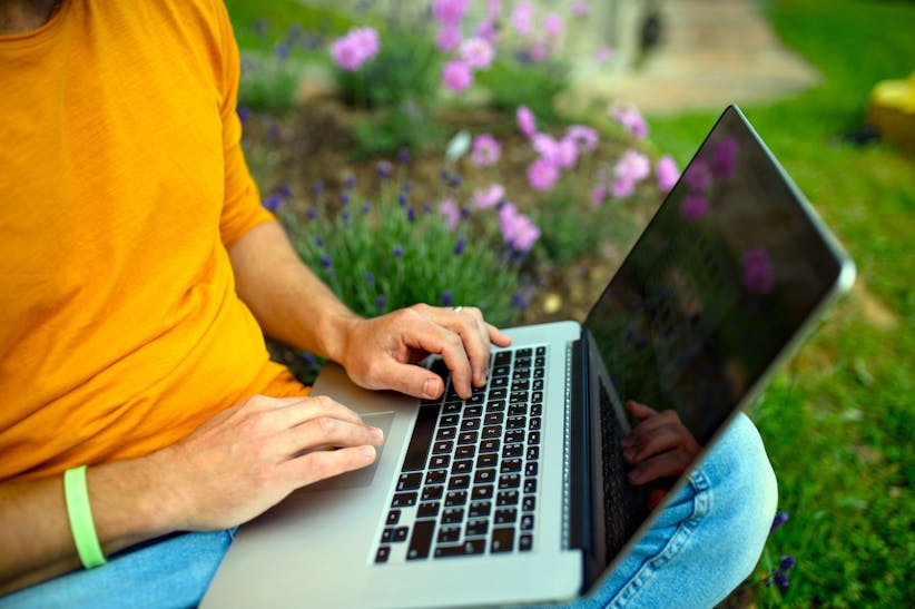 Person working on a laptop outside in a garden